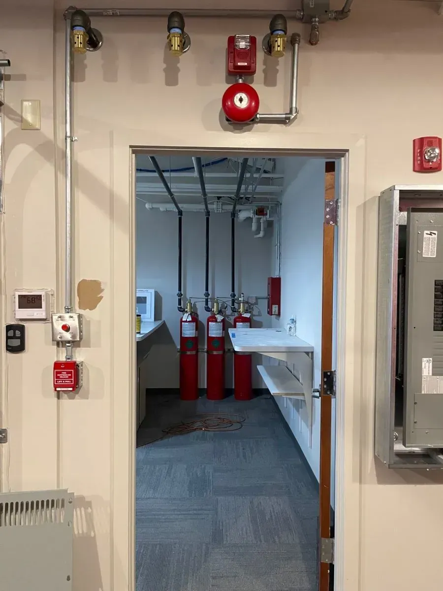 A doorway leading to a room with red fire extinguishers on the wall.