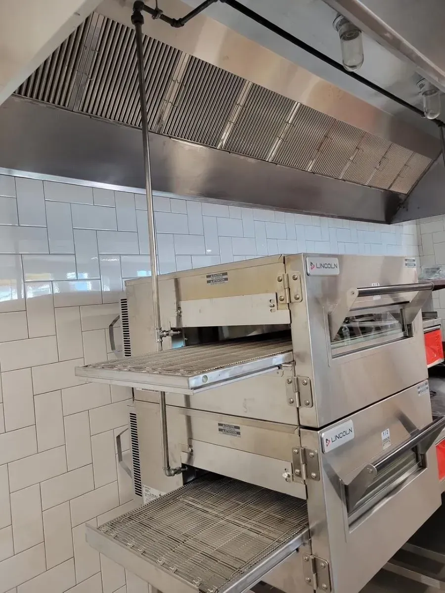 A stainless steel pizza oven is sitting in a kitchen.