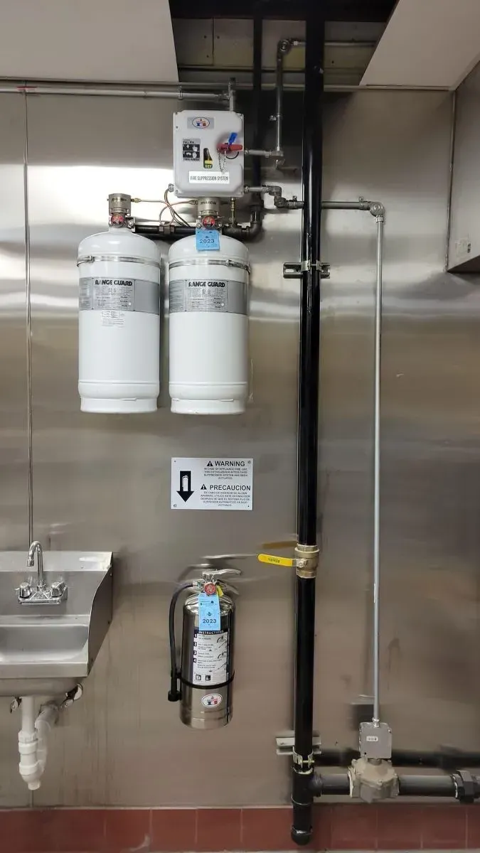 A kitchen with a sink and a fire extinguisher on the wall.