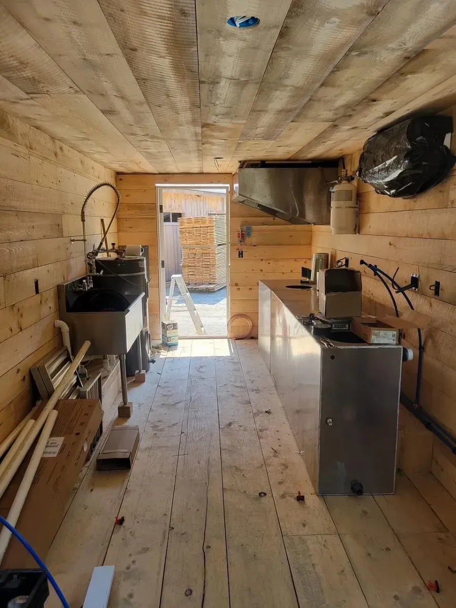 A kitchen with wooden walls and a stainless steel counter top.
