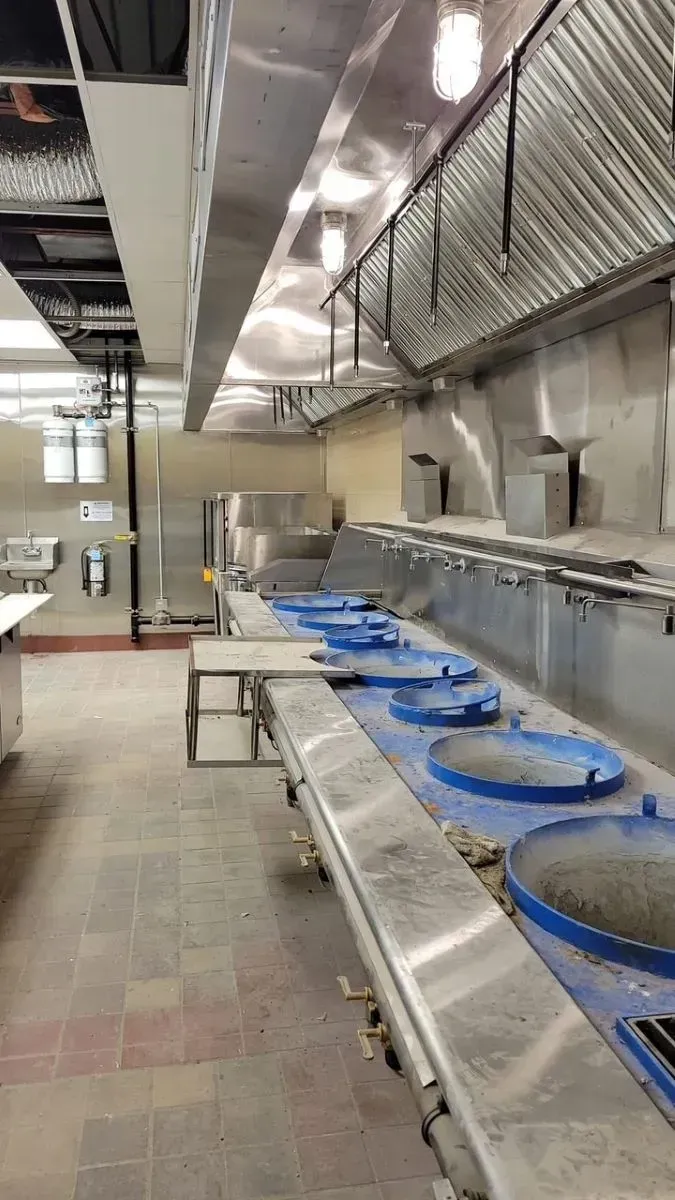 A large commercial kitchen with a lot of stainless steel appliances.