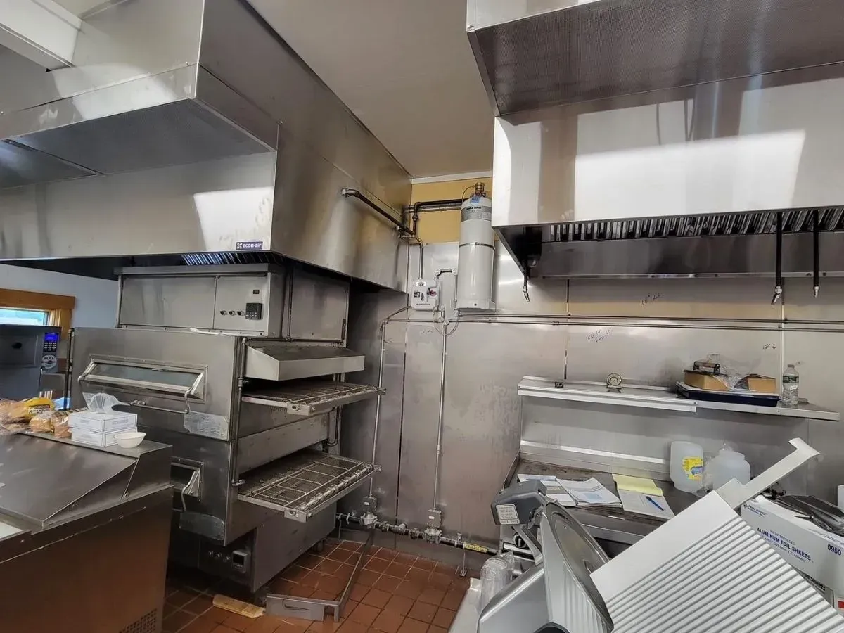 A kitchen with stainless steel appliances and a pizza oven.