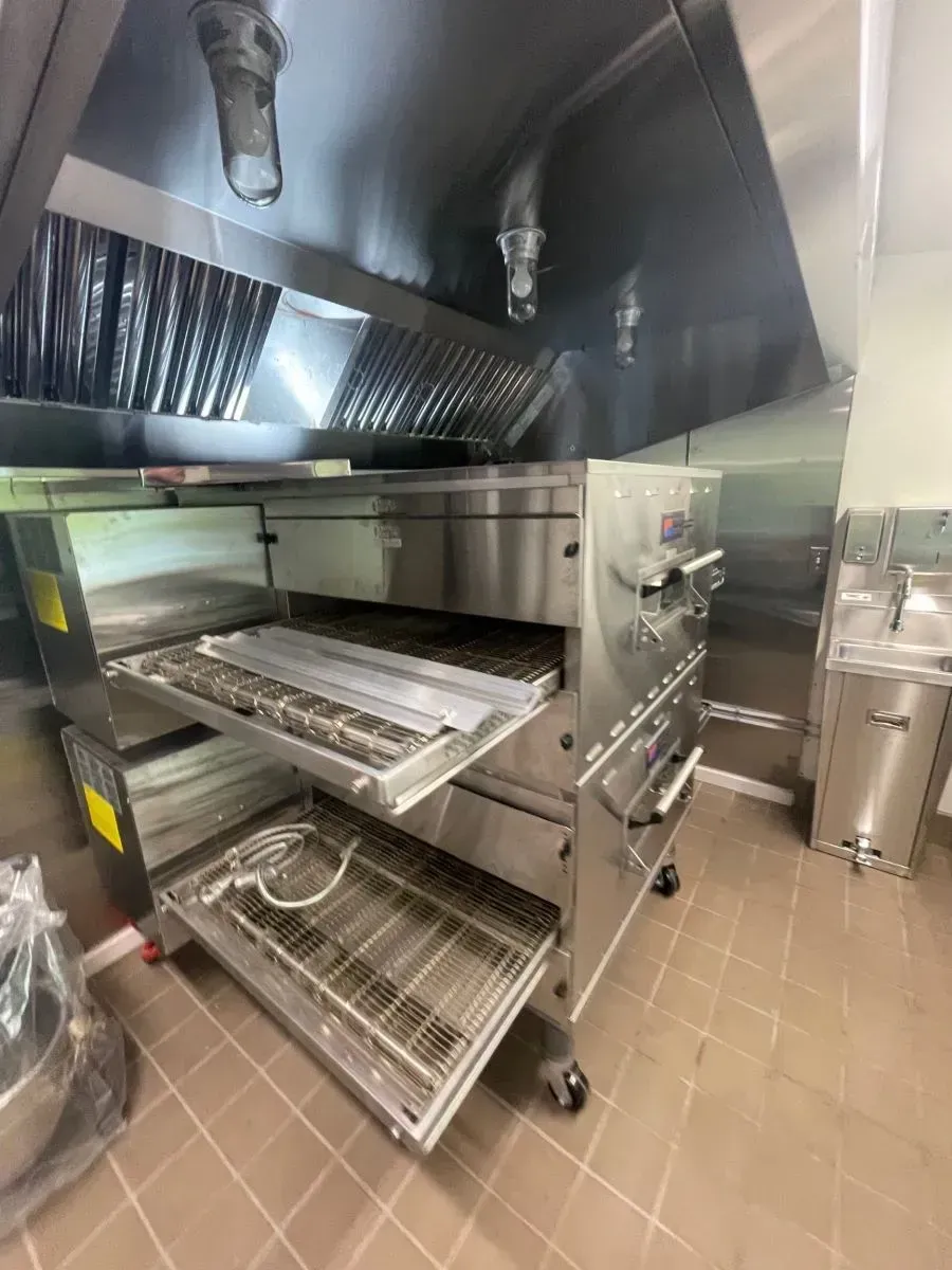 A stainless steel pizza oven is sitting in a kitchen.