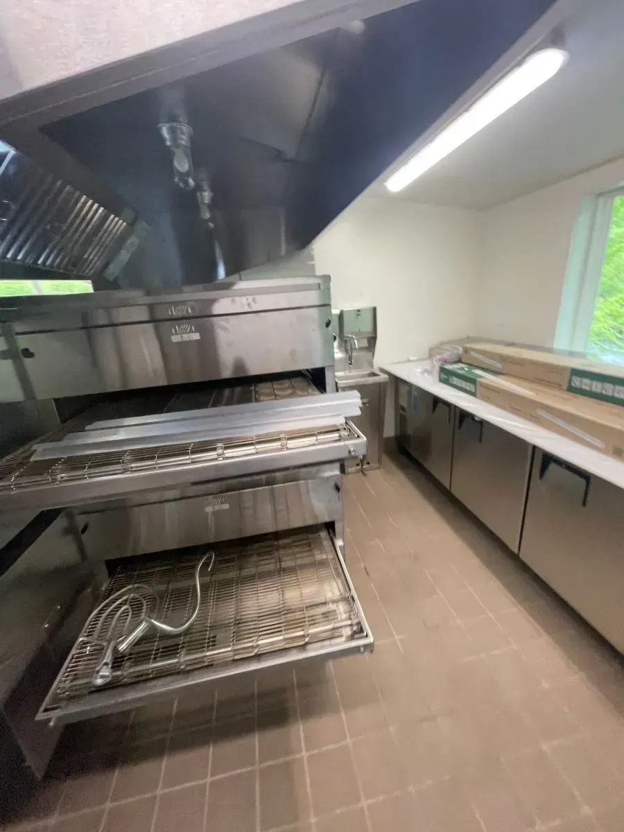 A kitchen with stainless steel appliances and a pizza oven