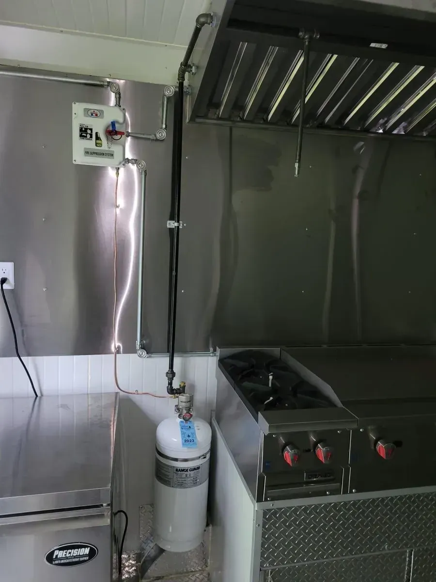 A stainless steel kitchen with a stove and a propane tank.