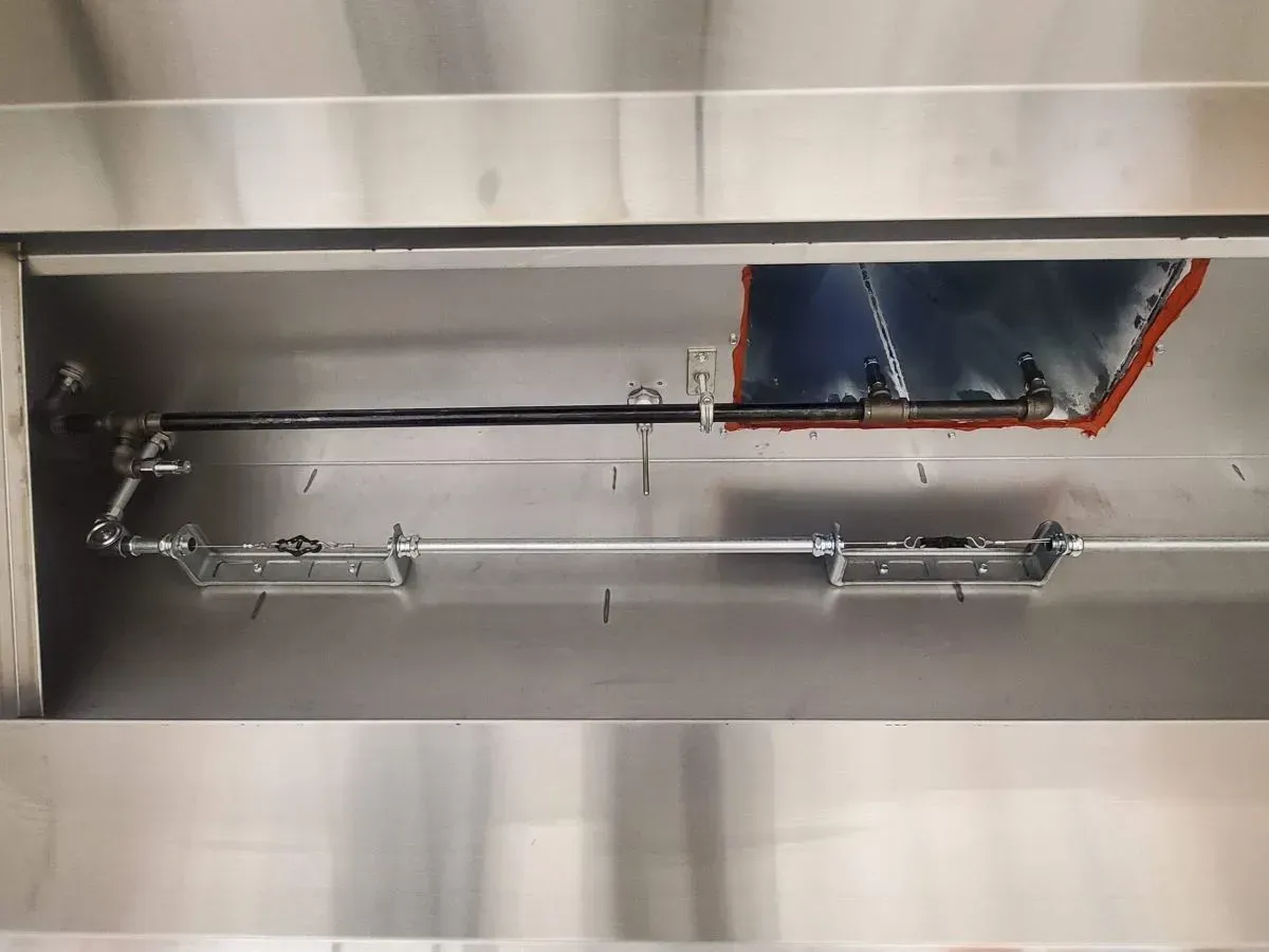 A stainless steel pipe is hanging from the ceiling in a kitchen.