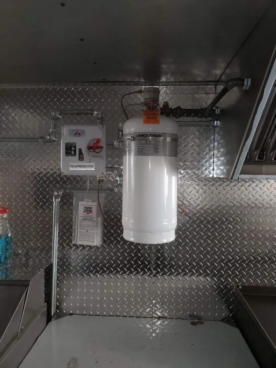 A white fire extinguisher is hanging from the ceiling of a kitchen.