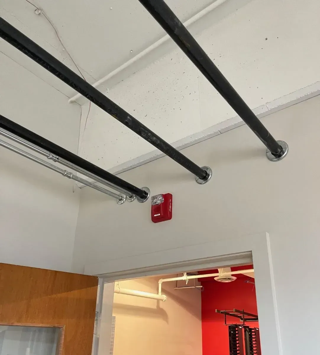 A red fire alarm is mounted on the wall above the door