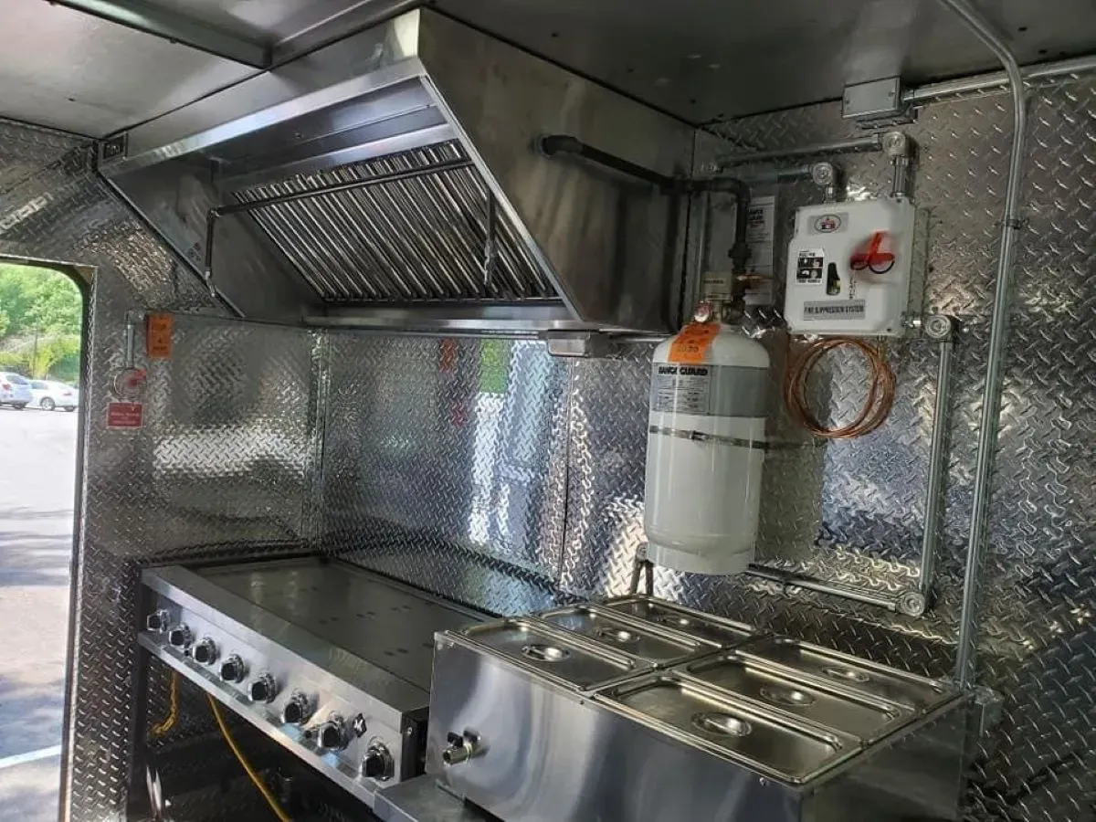 A stainless steel kitchen with a stove and a hood.