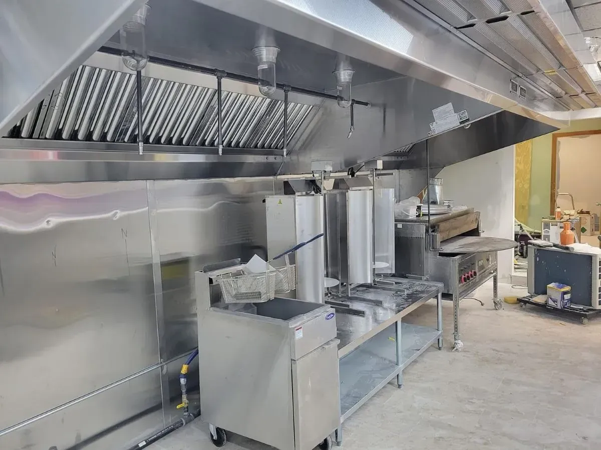 A kitchen with stainless steel appliances and a hood.