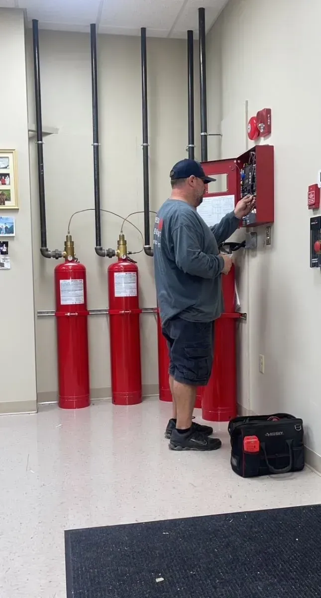 A man is working on a fire alarm system in a room.