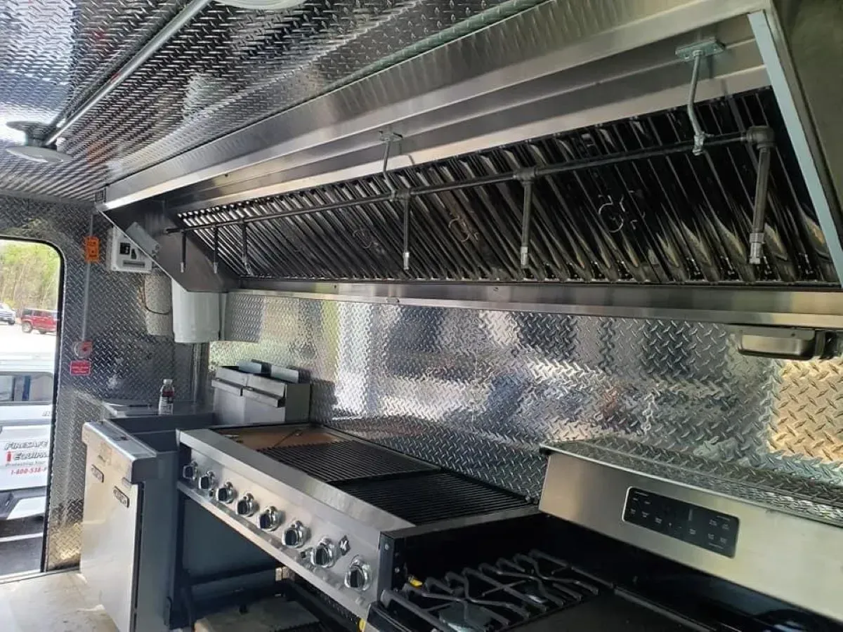 The inside of a food truck with stainless steel appliances and a stove.