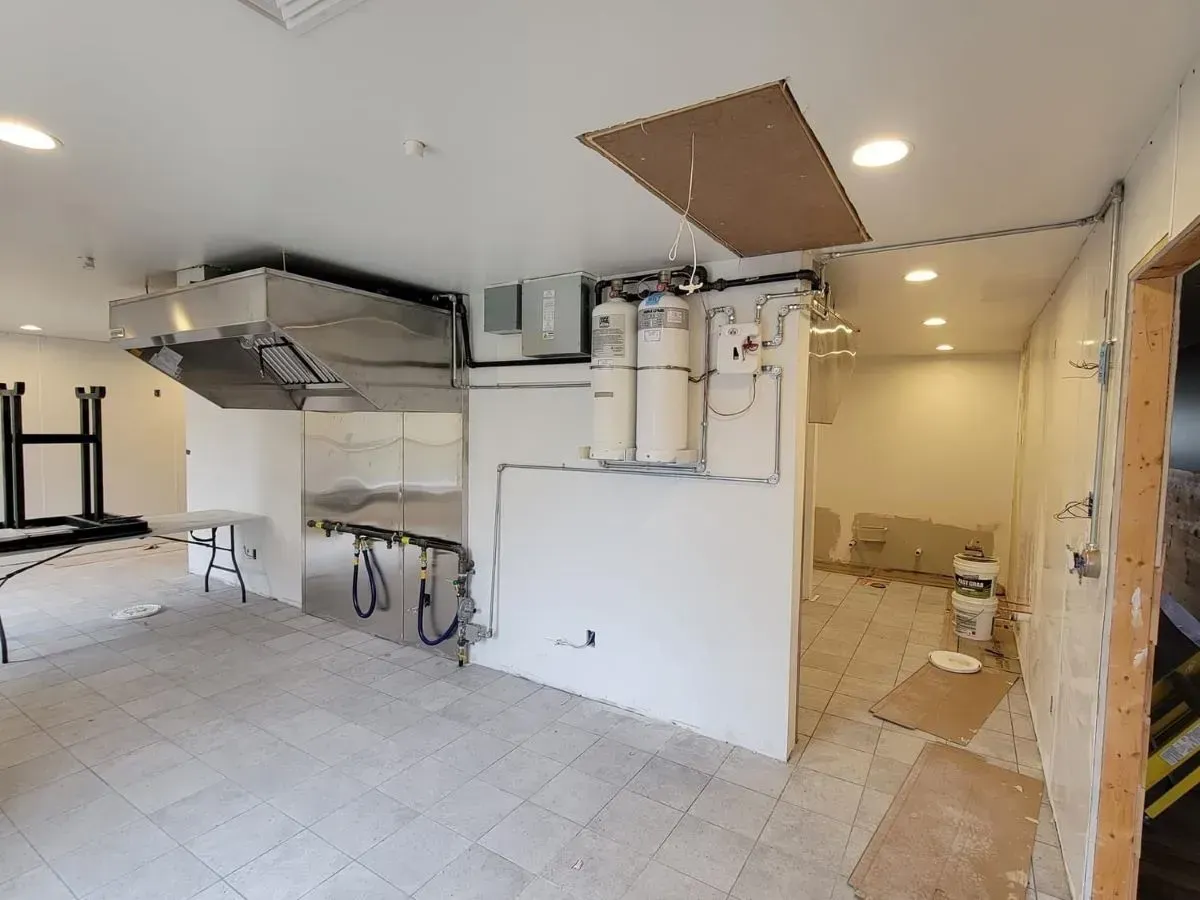 A large empty room with a stove and a table in it.
