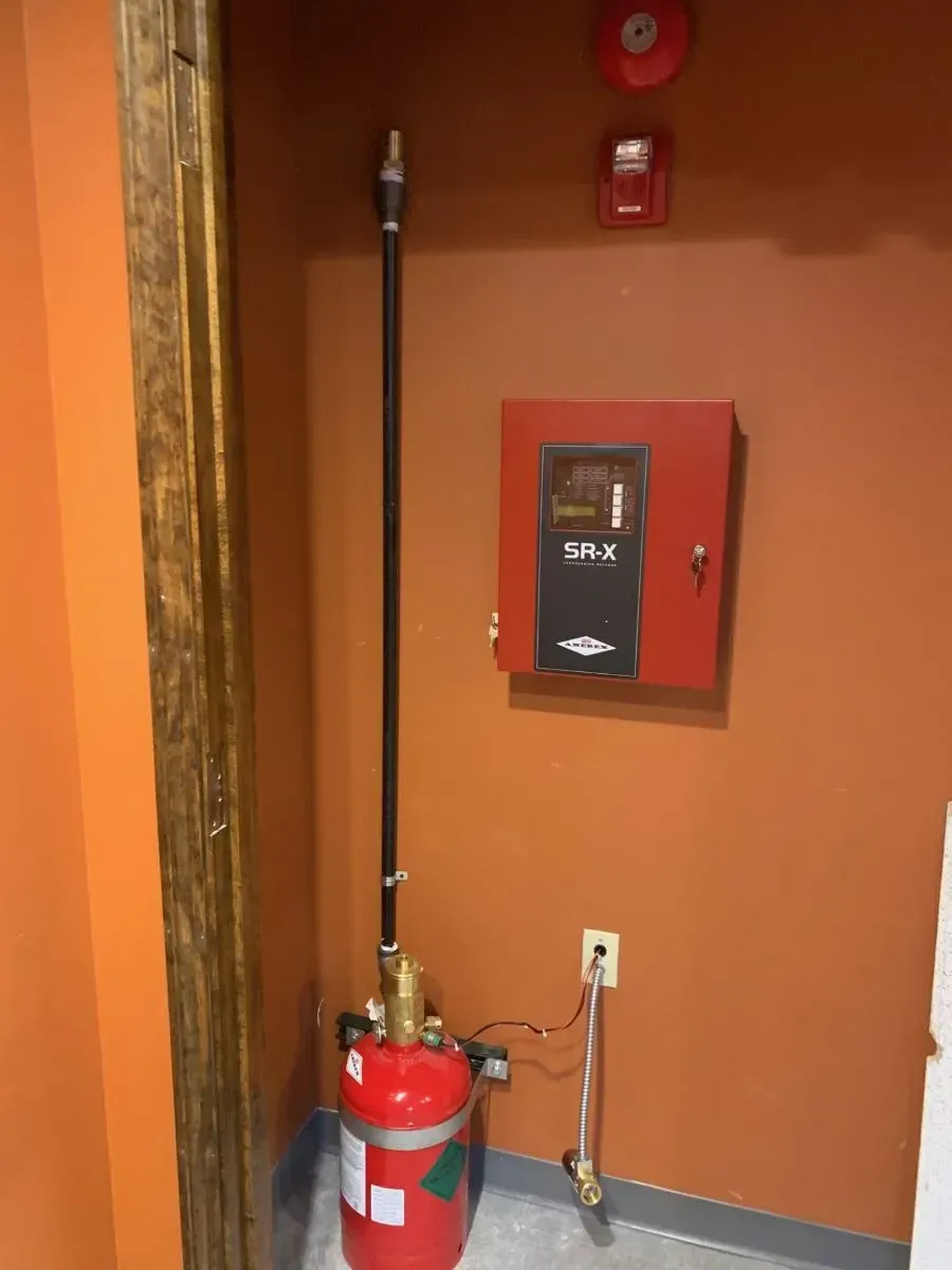 A red fire extinguisher is sitting next to a red box on a wall.