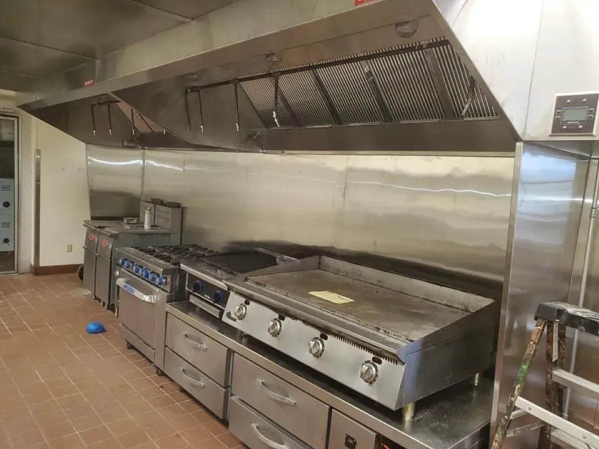A kitchen with stainless steel appliances and a hood.