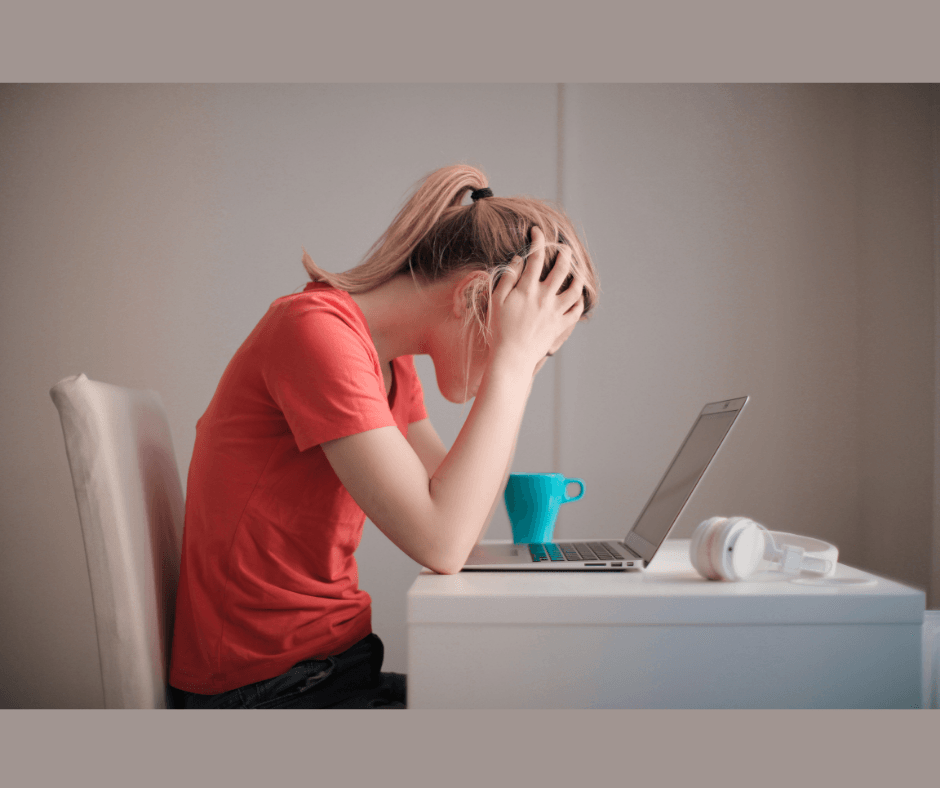 Girl sitting at desk with computer, hands on her head