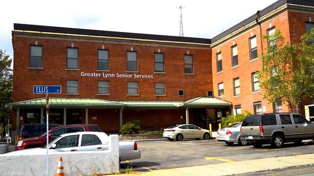 Brick building with parked cars in front and a blue street sign on the left