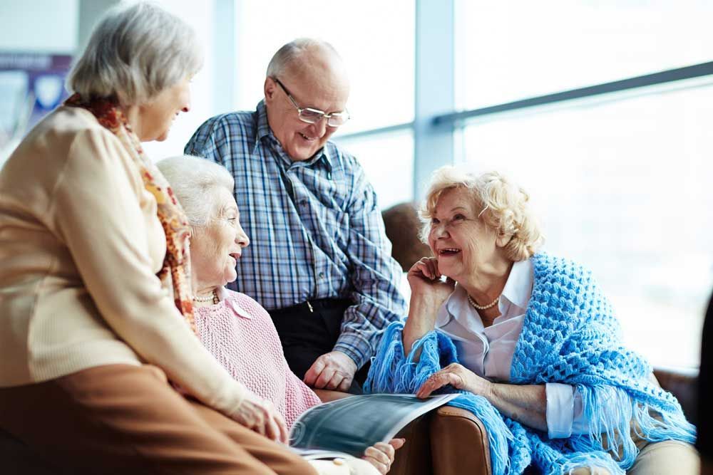Group of seniors chatting and smiling together in a bright lounge