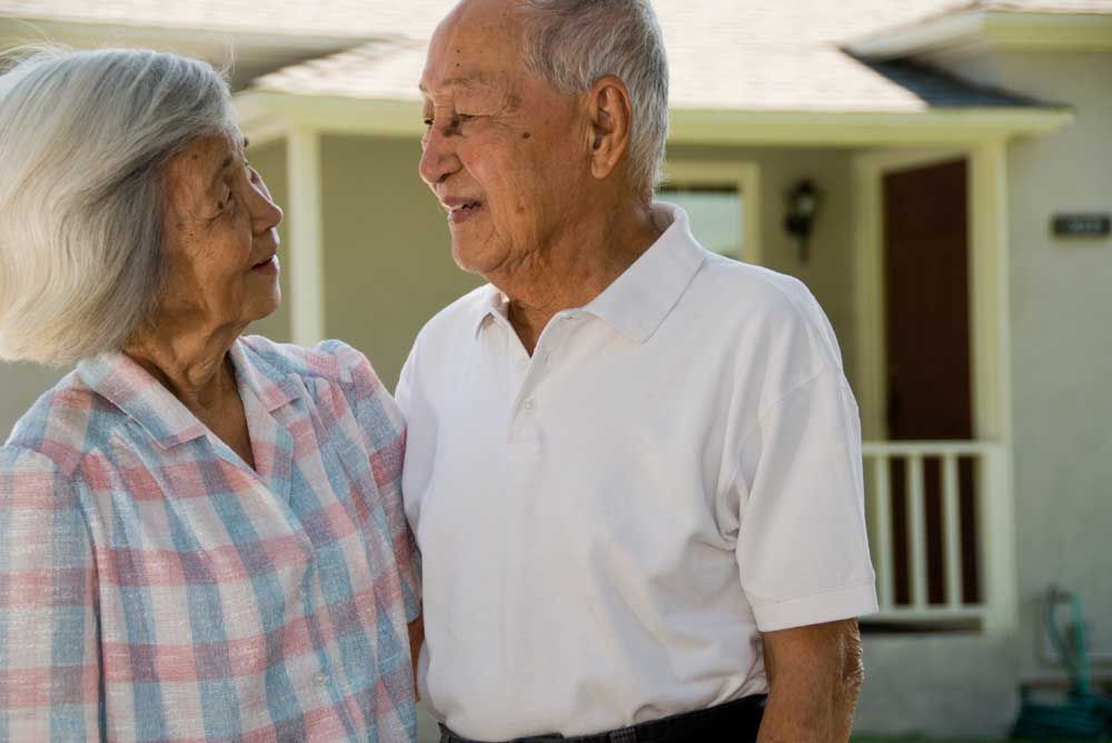 Asian couple in front of home.