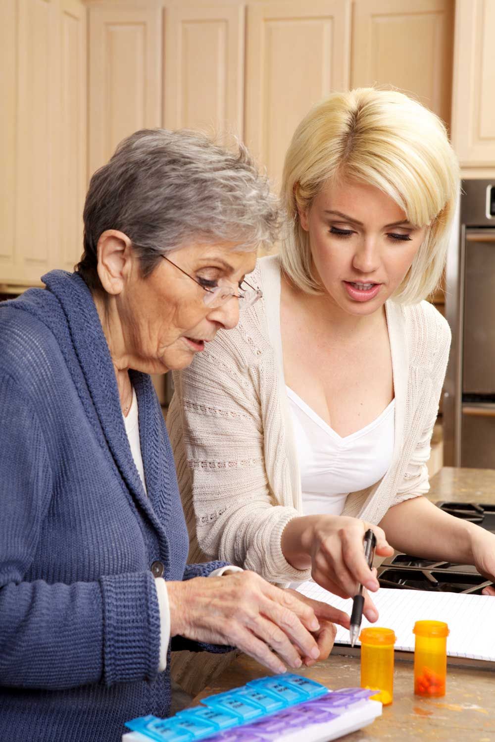 A younger woman helping an older woman with medication