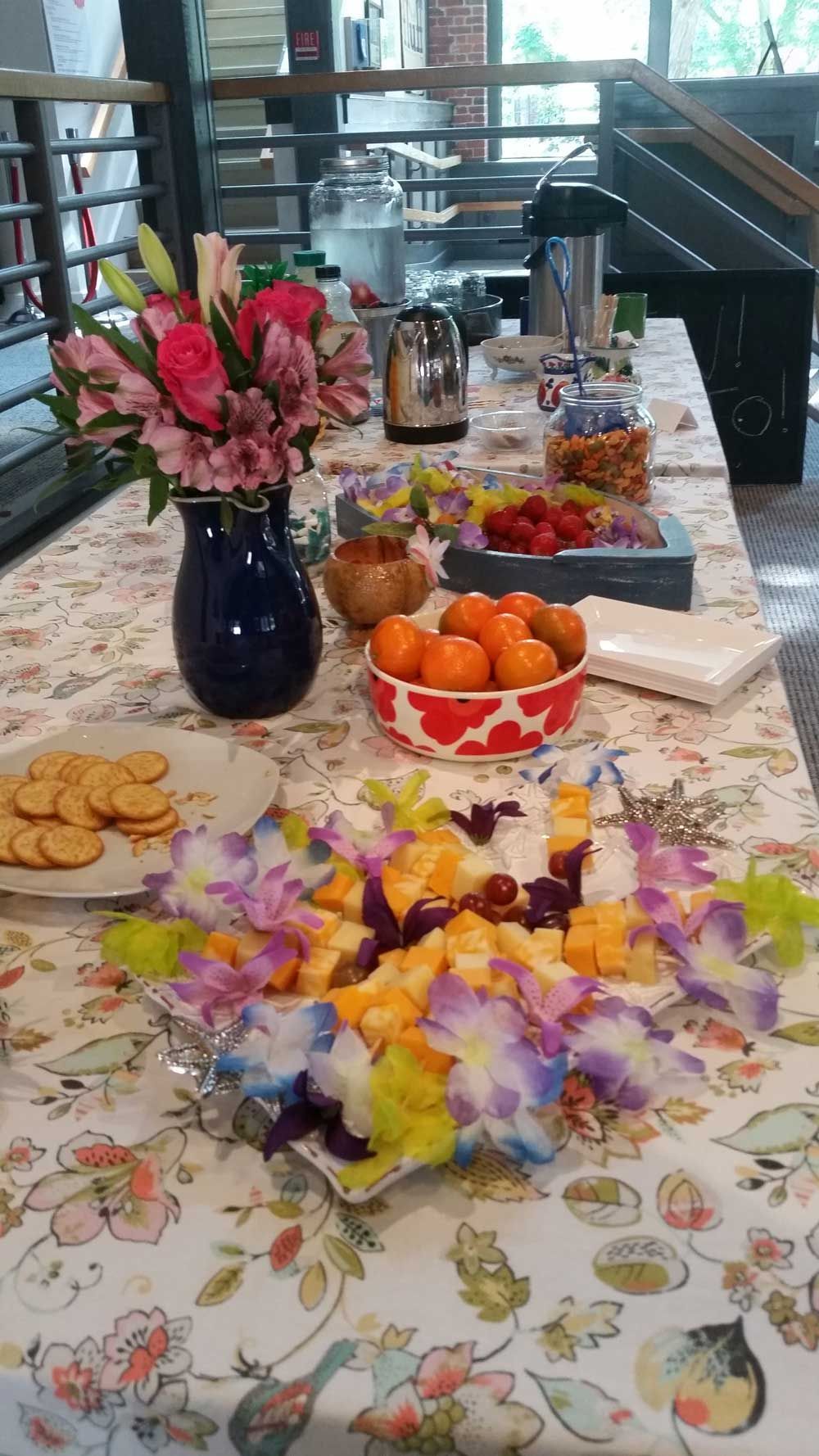 A table decorated with flowers and food and a bright table cloth