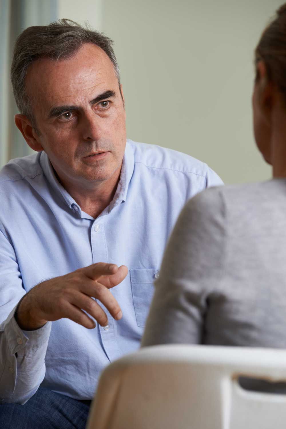 Man counseling someone in a chair.