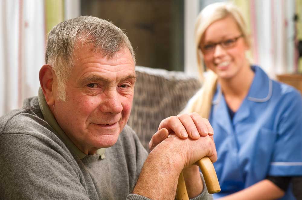 Older disabled man with young woman worker