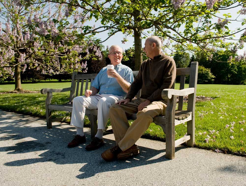 Two men sitting on a bench outside.