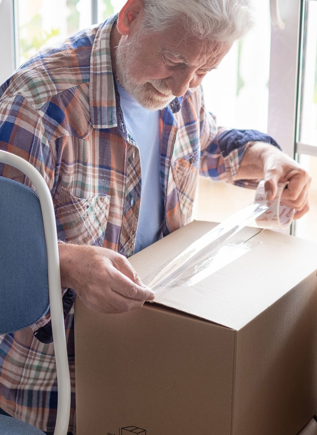 Man taping a moving box shut.