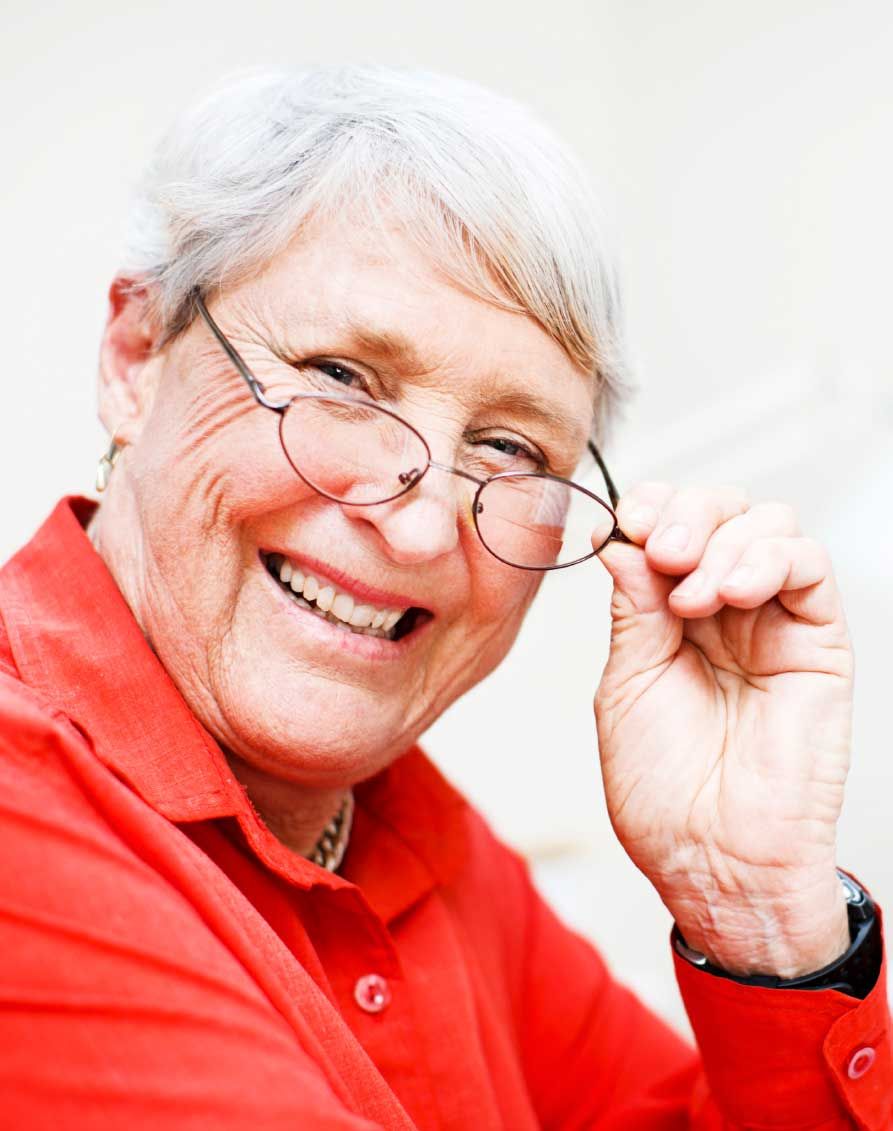 Woman in red shirt smiling, adjusting eyeglasses.