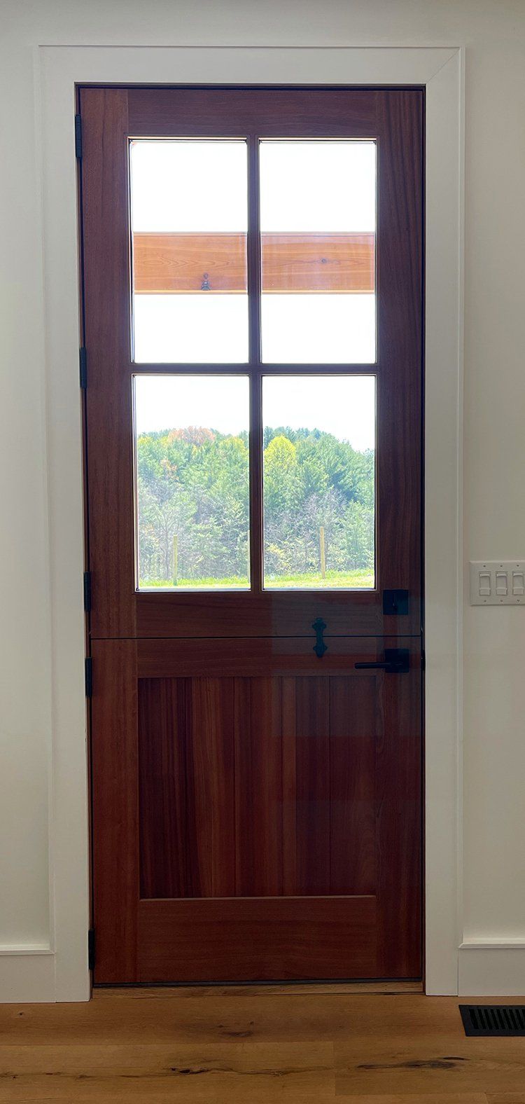 A wooden door with four windows and a view of a field.