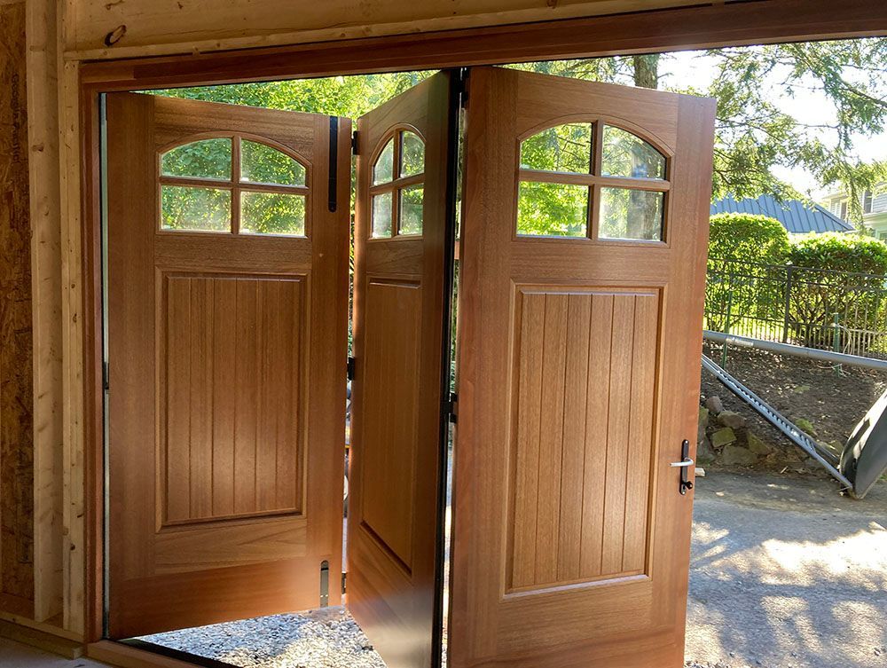 A wooden garage door is open to a driveway