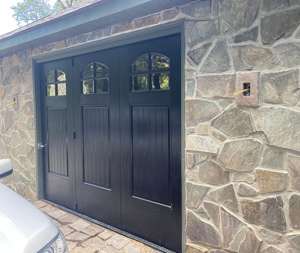 A car is parked in front of a black garage door.
