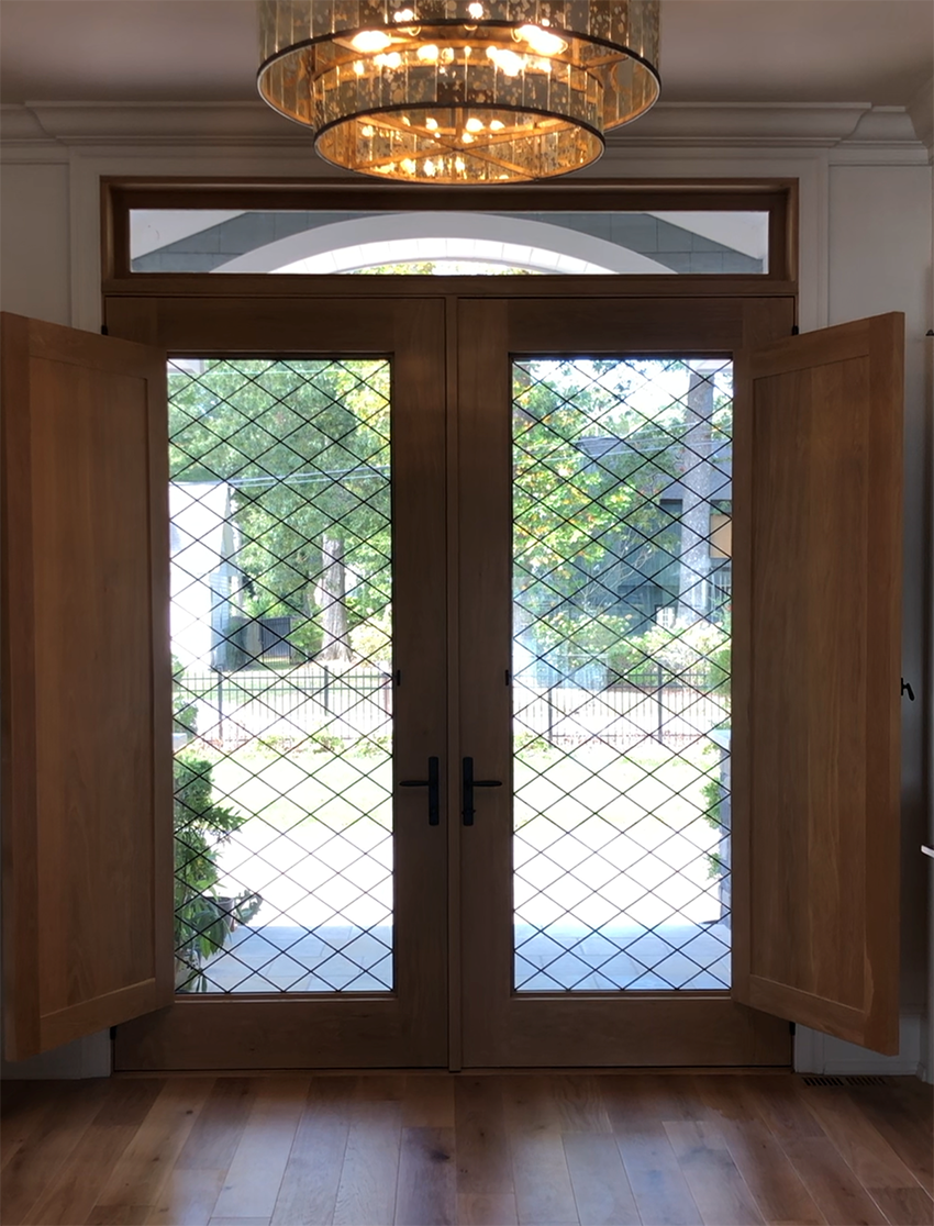 A room with a stained glass door and a chandelier hanging from the ceiling.