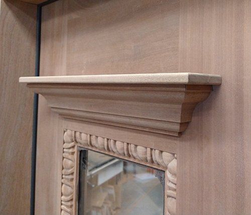 A wooden mantle with a mirror on top of it.