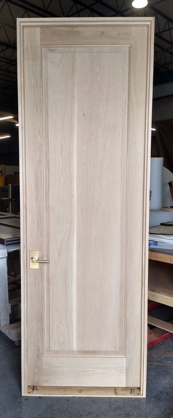 A wooden door is sitting on a concrete floor in a room.