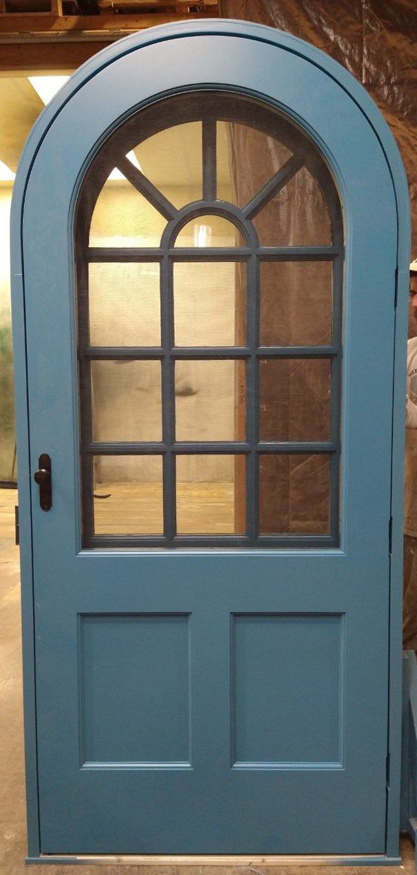 A blue door with a black frame and arched window.