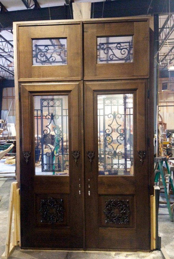 A pair of wooden doors with wrought iron trim are sitting in a warehouse.