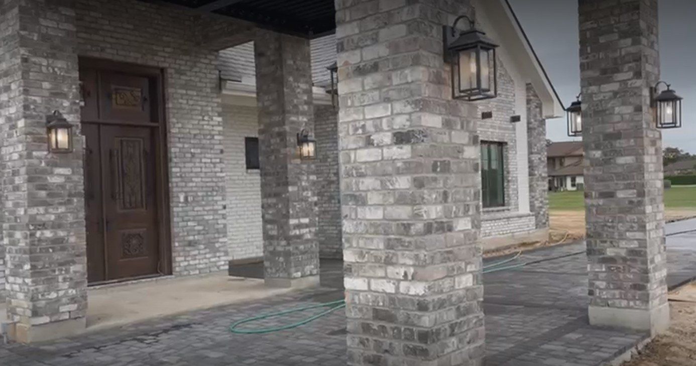 The front of a house with brick columns and a porch.