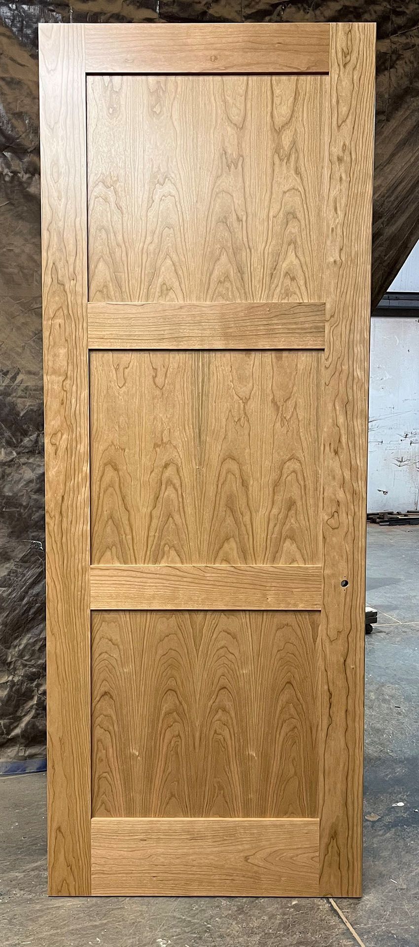 A wooden door is sitting on a cement floor in a room.