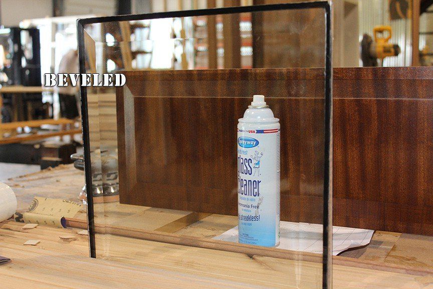 A spray bottle is sitting on a wooden table next to a glass frame.