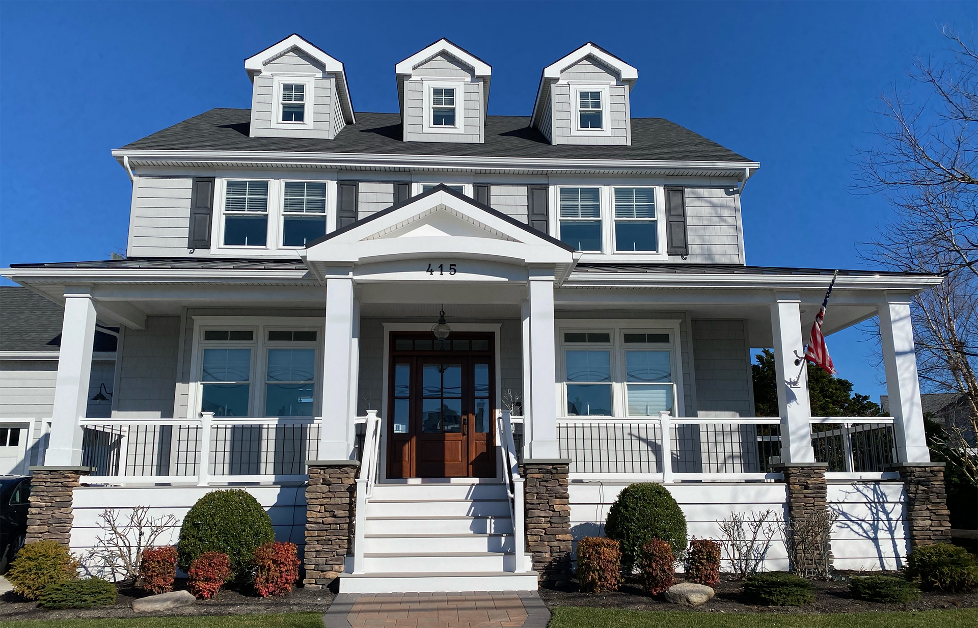 A large white house with a large porch on a sunny day