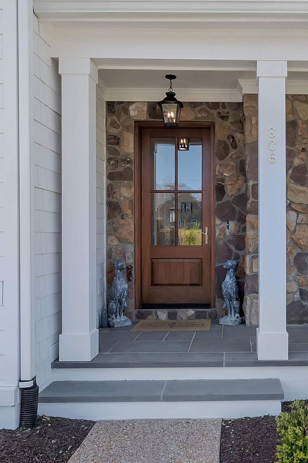 The front door of a house with a stone wall and a wooden door