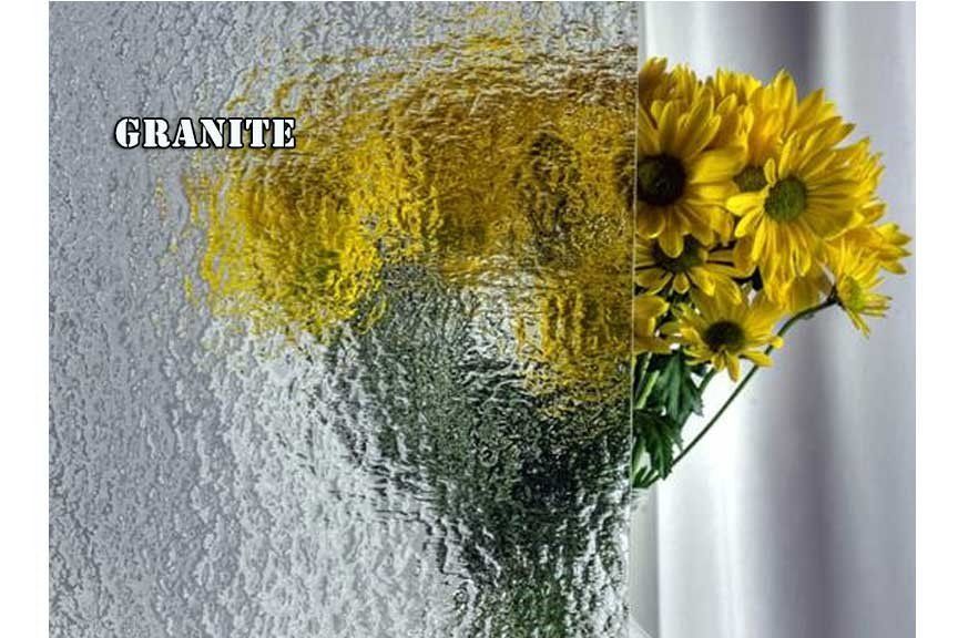 A vase filled with yellow flowers is sitting in front of a window.