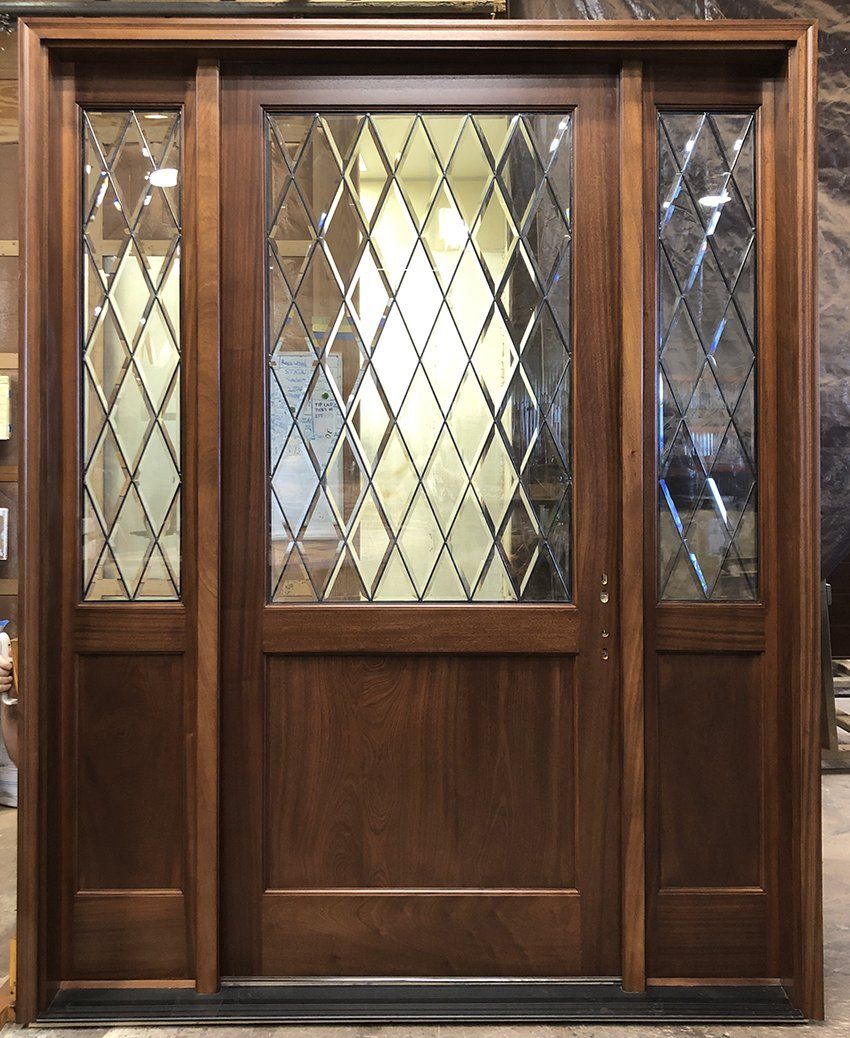 A wooden door with stained glass on it is sitting in a room.