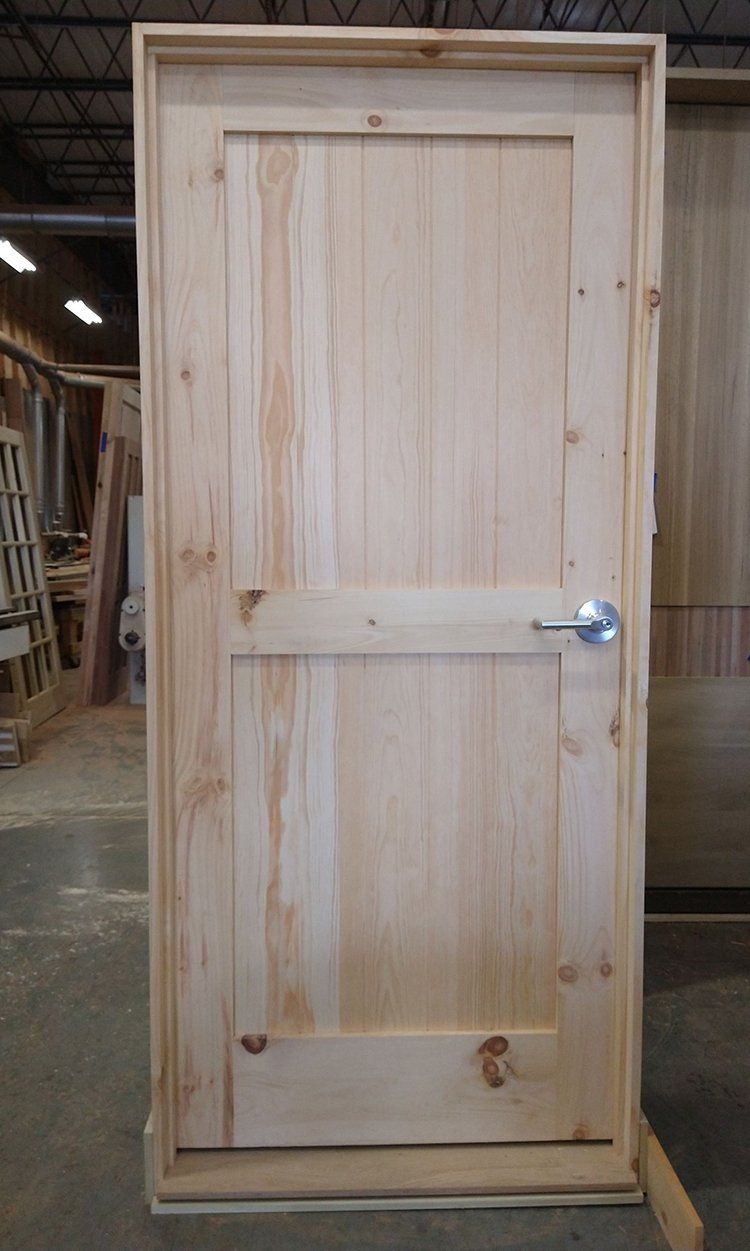 A wooden door is sitting on top of a concrete floor in a woodworking shop.