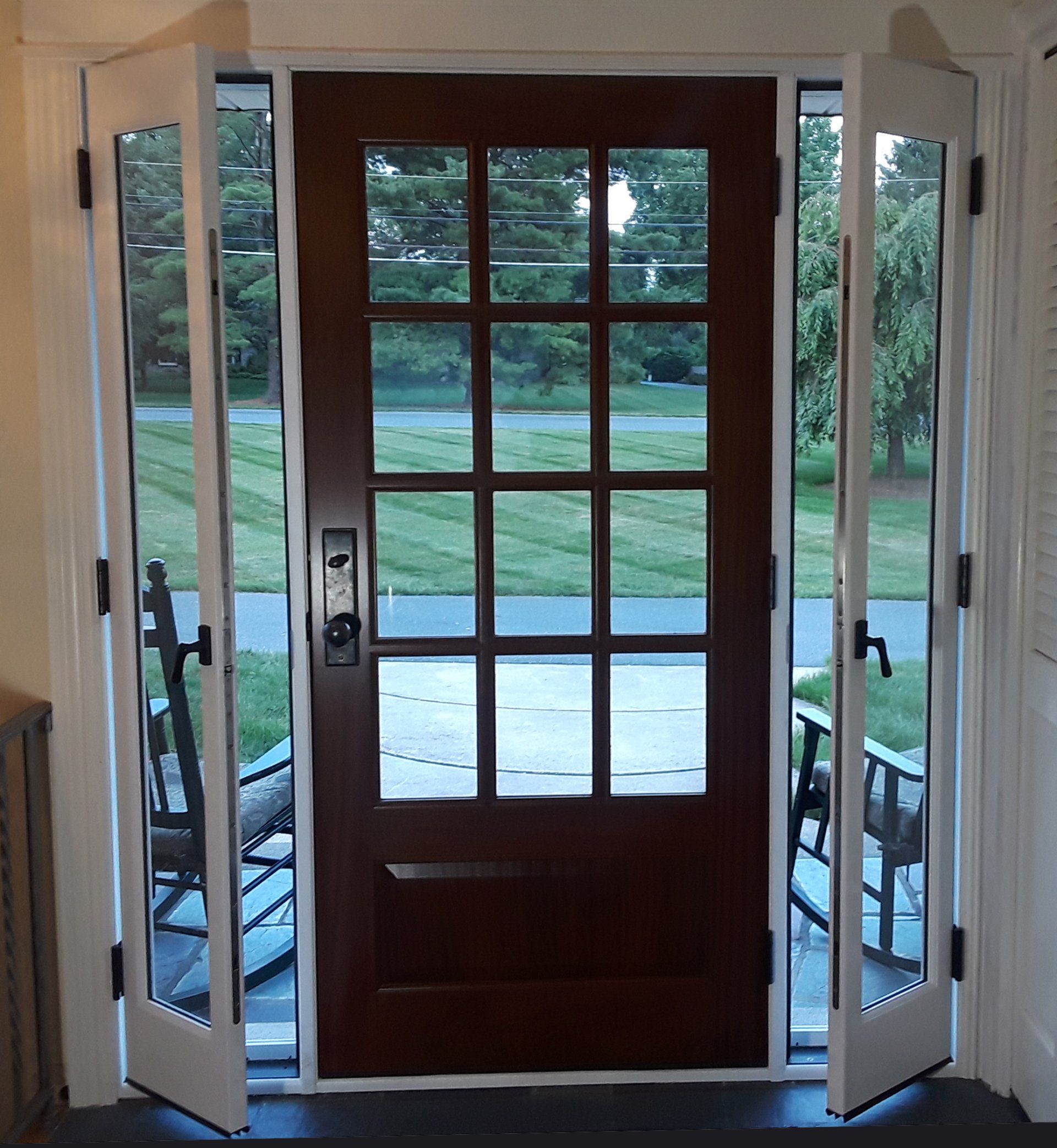 The front door of a house is open to a lush green field