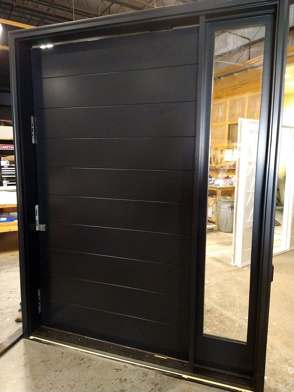 A black door is sitting on a concrete floor in a room.