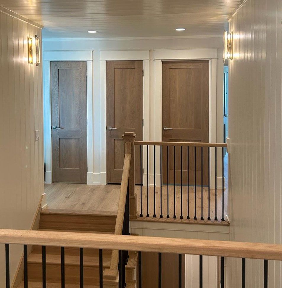 A hallway with stairs leading up to the second floor and a railing.
