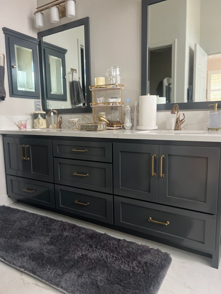 Black double vanity with gold hardware, white countertop, mirrors, and decor in a modern bathroom